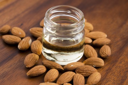 Almond oil with nuts on wooden background